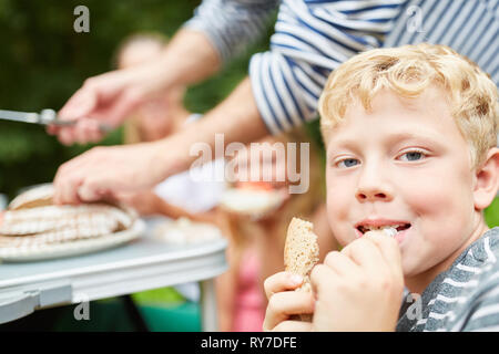 Ragazzo mangia un pezzo di pane a colazione sul campeggio durante le vacanze estive Foto Stock