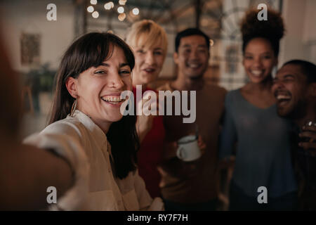 Ridere amici prendendo selfies insieme in un bar di notte Foto Stock