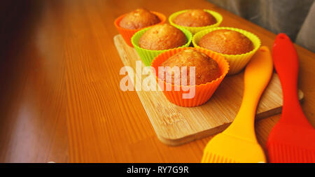 Una semplice mini muffin in silicone colorate bakeware. Coppa in silicone la cottura tortine e spazzole in silicone. La cucina e il concetto di cucina a vista su sfondo di legno Foto Stock