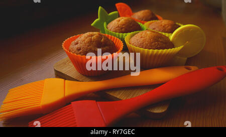 Una semplice mini muffin in silicone colorate bakeware. Coppa in silicone la cottura tortine e spazzole in silicone. La cucina e il concetto di cucina a vista su sfondo di legno Foto Stock