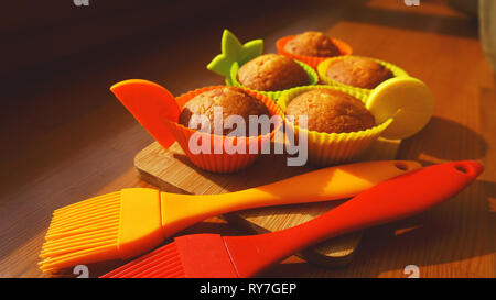 Una semplice mini muffin in silicone colorate bakeware. Coppa in silicone la cottura tortine e spazzole in silicone. La cucina e il concetto di cucina a vista su sfondo di legno Foto Stock