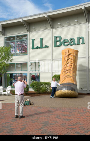 I visitatori di prendere una foto ricordo con il novantesimo anniversario bean boot nella parte anteriore del LL Bean store in Freeport, Maine, Stati Uniti d'America. Foto Stock