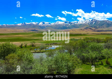 Kochkor Chuy Valley Paesaggio con fiume di erba e terra Snow capped Terskey Ala troppo la gamma della montagna Foto Stock