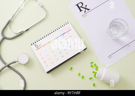 Uno stetoscopio con farmaci e pillole sulla pagina del calendario Foto Stock