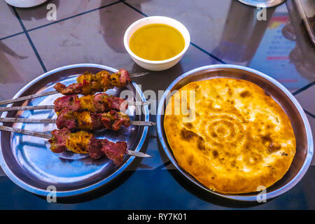 Tradizionale uigura Piccante spiedini di agnello con cumino tazza di tè e pane Naan Foto Stock