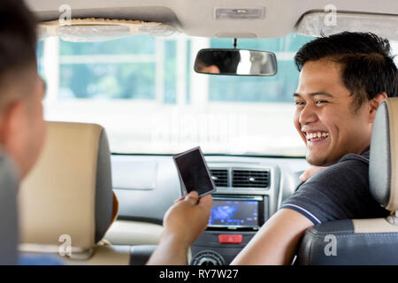 Online taxi driver, il trasporto, il concetto di viaggio - attraente uomo asiatico guardando al cliente che mostra carta di credito per il pagamento all'interno dell'auto Foto Stock