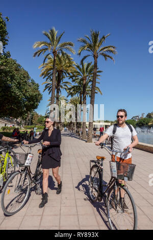 Valencia Turia Park, gente che spinge biciclette in giardino con palme, Spagna bicicletta Foto Stock