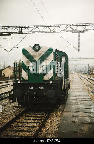 Dettagli della grande e verde locomotiva, parcheggiato nella stazione durante il maltempo, freddo giorno di pioggia. Foto Stock