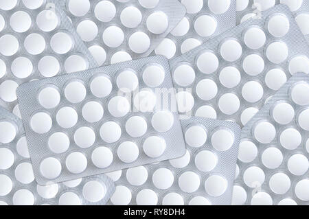 Bianco pillole tonda in confezioni sono sparsi sulla superficie. Close-up. Foto Stock