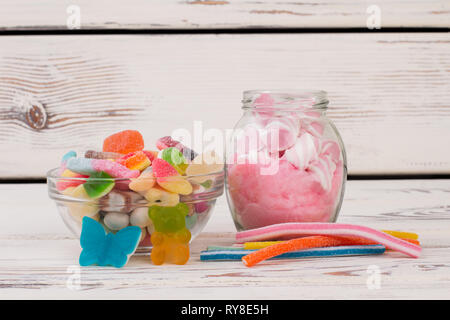 Caramelle multicolore e gelatine su sfondo di legno. Foto Stock