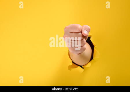 Pugno ha rotto il giallo della parete di carta Foto Stock