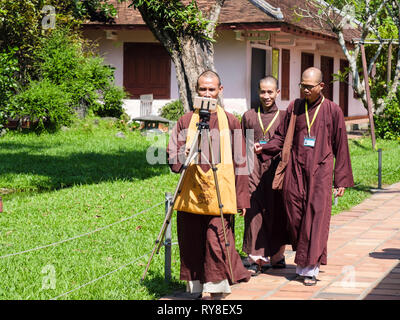 Monaci e a piedi prendendo un selfie su un telefono mobile a Thien Mu Pagoda complesso. Tinta, Thừa Thien Hue, Provincia del Vietnam, in Asia Foto Stock