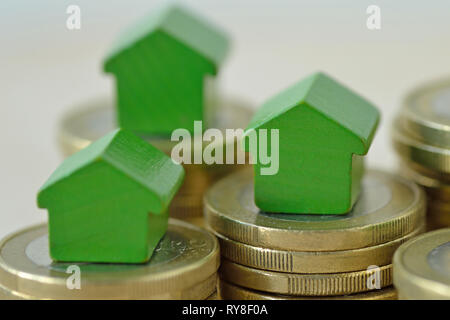 Verde case in miniatura su pile di monete - Nozione di investimento immobiliare, ipoteca, casa di assicurazione e prestito, eco-friendly house Foto Stock