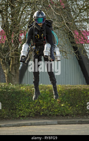 BASINGSTOKE, Regno Unito - 11 Marzo 2019: ginnasta pilota girata Ryan Hopgood dimostrando una gravità Industries jet pack volando attraverso un parco auto al Basings Foto Stock