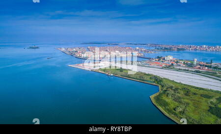 La città costiera di Chioggia in una antenna fuco girato con la grande pista da un lato e le case su altre isole in Italia Foto Stock