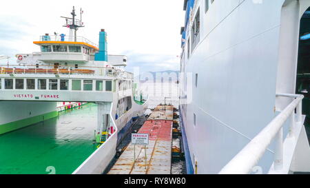 La parte laterale della grande nave passeggeri nel porto di Messina in Sicilia Italia sul lato della piattaforma con catene arrugginite galleggiante sul lato Foto Stock