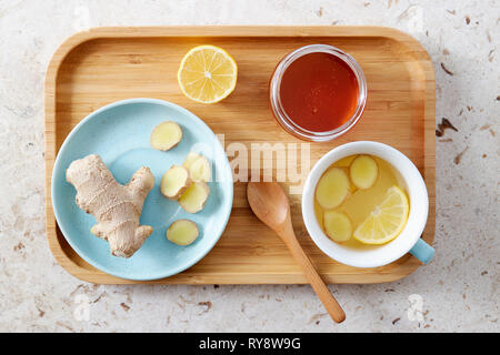 Limone e tè allo zenzero con il miele. Vassoio in legno di miele tè al limone con zenzero fresco. Foto Stock