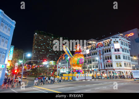 Pedoni in crosswalk su Cross Street, con il gigante Lanterna Gallo - Chinatown, Singapore Foto Stock