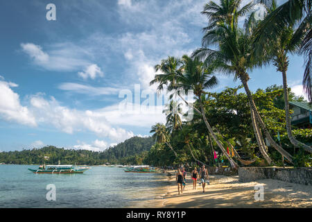 Il tour europeo gruppo camminare sotto le palme da cocco sulla spiaggia - Porto Barton, Palawan - Filippine Foto Stock