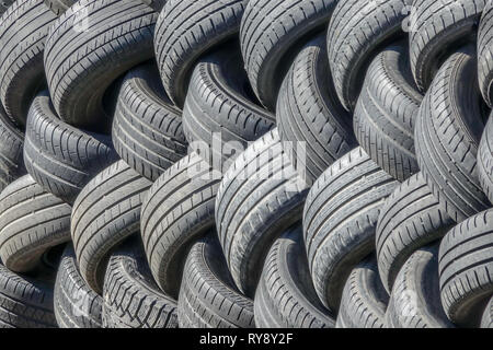 Vecchi pneumatici usati che sono allineati in una pila. Foto Stock