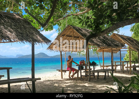 Turista olandese uomo bere in Bamboo Beach Hut Linapacan Isola, Palawan - Filippine Foto Stock