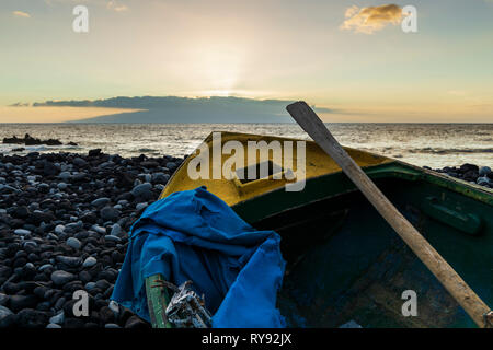 In legno barca a remi su terreni sassosi spiaggia al tramonto con isola all'orizzonte, Fonsalia, Tenerife, Isole Canarie, Spagna Foto Stock