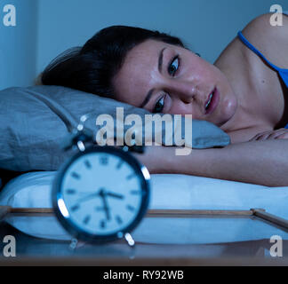 Insonne e disperato bella donna caucasica sveglio di notte non è in grado di dormire, sentendosi frustrato e preoccupata guardando alla sofferenza di clock da ins Foto Stock