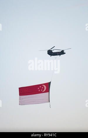 CH-47 Chinook elicottero militare portando una grande bandiera di Singapore. Il Marina Bay, Singapore Foto Stock