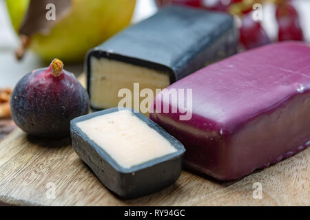 Mini nero e rosso scuro cerata formaggi cheddar realizzato da ovest paese latte e secolare e metodi in Inghilterra da vicino Foto Stock