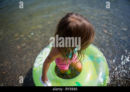 Angolo di Alta Vista della ragazza con anello gonfiabile in piedi nel lago durante la giornata di sole Foto Stock