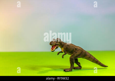 Dinosauro giocattolo in una foresta giocattolo. come un vero e proprio T-rex su uno studio luminoso dello sfondo con alberi di legno. Eco giocattoli. Foto Stock