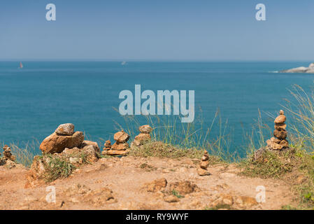 Pila di pietre su Promthep cape con il mare delle Andamane sullo sfondo, Phuket, Tailandia Foto Stock