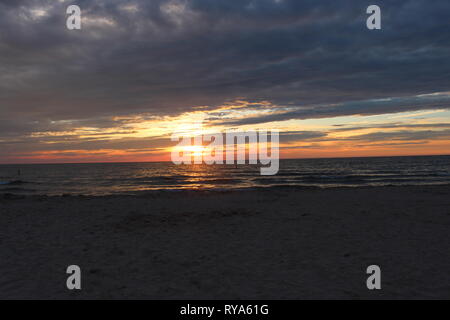 Giocare sulla spiaggia tutto il giorno, nuotare fino a quando non sei contenuti per poi trascorrere la serata con alcuni cari, e guardare uno spettacolo di luci come il sole tramonta. Foto Stock