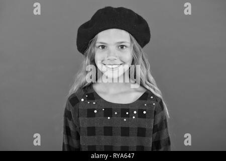 Kid poco carino ragazza sorridente in posa di hat sfondo rosso. Moda beret accessorio per la femmina. Come indossare il francese beret. Beret style inspirat Foto Stock