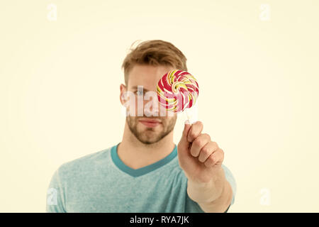 Man tenere grandi sweet lollipop davanti al suo volto. Uomo Barbuto ama i dolci. Guy offre giant lollipop candy. Lecca-lecca leccare uno di grande tecnica orale Foto Stock