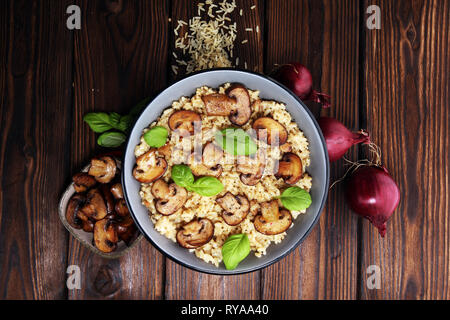 Risotto con funghi, erbe fresche e formaggio parmigiano e basilico Foto Stock