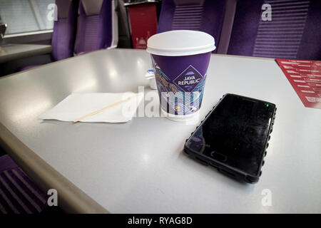 Caffè e smartphone su enterprise treno tra Belfast e Dublino attraversando la Repubblica di Irlanda Irlanda del Nord confine Foto Stock