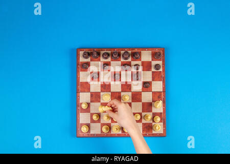 Il capretto con le mani su una scacchiera giocare a scacchi gioco su sfondo blu, vista dall'alto Foto Stock