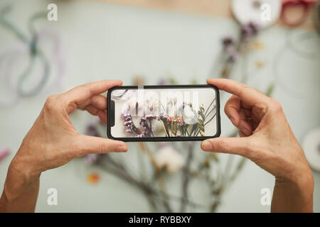 Sopra Visualizza Ingrandimento di un irriconoscibile donna prendendo mobile photo di composizione floreale in art studio, spazio di copia Foto Stock