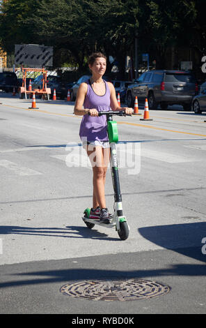 Equitazione donna un elettrico e scooter a noleggio, South Congress Avenue, Austin, Texas Foto Stock