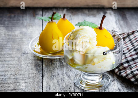 Dolce pera affogata con gelato alla vaniglia sul tavolo di legno Foto Stock