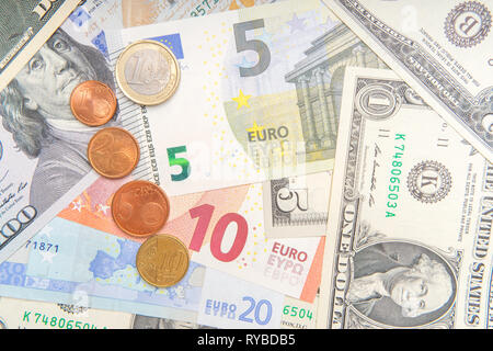 Gruppo di monete su sfondo di vari Euro e Dollaro banconote. Foto Stock