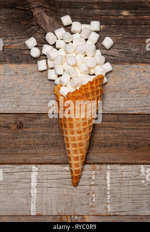 Marshmallow nel cono di wafer sul tavolo di legno Foto Stock
