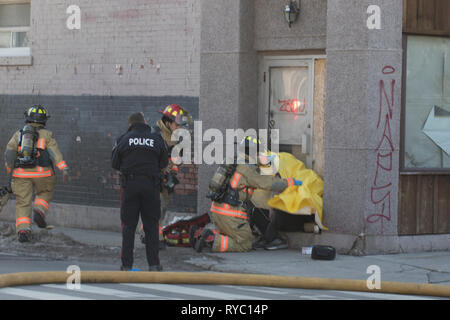 Hamilton, Canada 2019: Vigili del fuoco e polizia di occuparsi di una vittima di inalazione di fumo dopo un edificio con appartamenti fire. Il salvataggio di persone da un incendio. Foto Stock