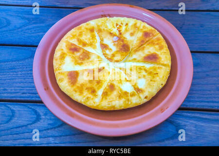 Moldavo Placinta tradizionale pasticceria salata con ripieno di formaggio su un colore rosso piastra ceramica Foto Stock