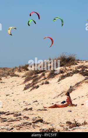 TRAFALGAR, Spagna - 14 settembre 2008 - Tourist rilassante sulla spiaggia con kitesurfisti al posteriore, Cabo Trafalgar, la provincia di Cadiz Cadice, Andalusia, Spagna Foto Stock