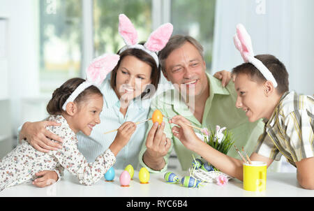 La famiglia felice di quattro indossando orecchie di coniglietto e pittura delle uova di Pasqua Foto Stock