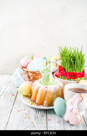 Pasqua impostazione tabella concetto, mensa conviviale con decorazione di erba Giovane, torta, color pastello di uova, biscotti a forma di uova, bunny rabbit Foto Stock