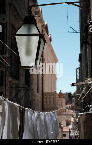Un vecchio e rustico lampada di strada in una città vecchia strada laterale con lavaggio pende da una linea di lavaggio in background, Dubrovnik, Croazia Foto Stock