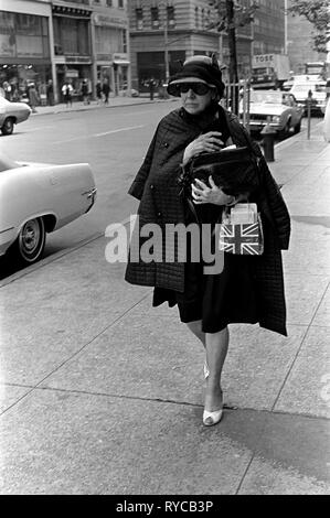 Manhattan street scene degli anni sessanta la moda più anziani vestiti alla moda donna porta una bandiera dell'Union Jack borsa a mano come ella si appresta a un appuntamento. 1969 60s USA US HOMER SYKES Foto Stock